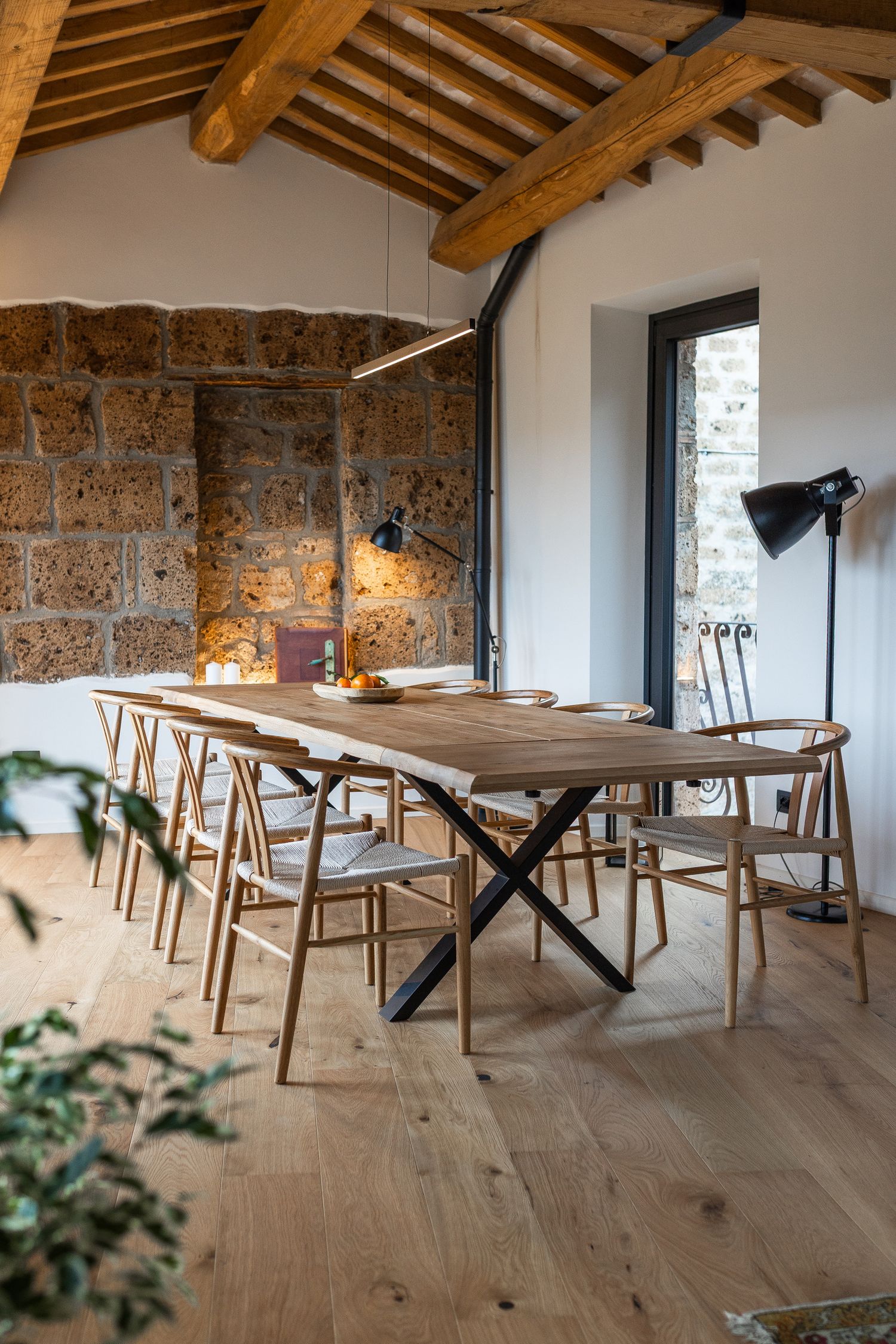 Shared dining and work table with stone wall and timber ceiling